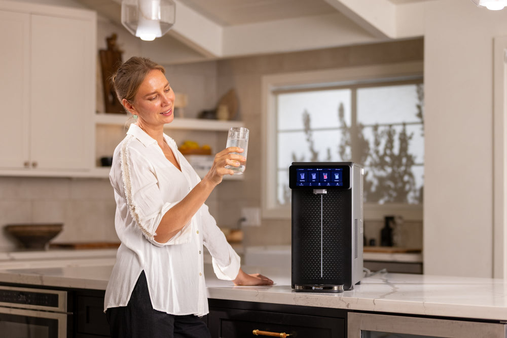 Woman smiling at a glass of sparkling water beside a black Sparkle